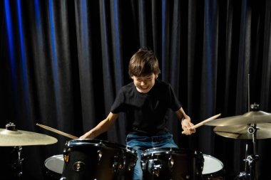 Bir çocuk kayıt stüdyosunda davul çalıyor.