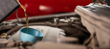Otomobil tamircisi araba motoruna yağ döker.
