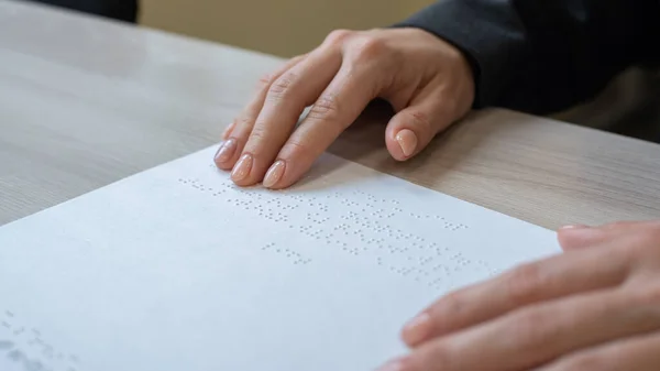 クローズアップの女性は、視覚障害者にテキストを読み上げます。女性は点字コードの紙を手に取る. — ストック写真