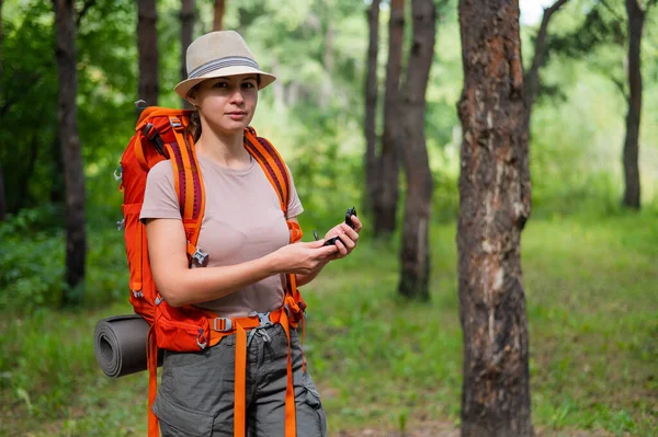 Jeune femme caucasienne fait de la randonnée et utilise une boussole dans la forêt. — Photo