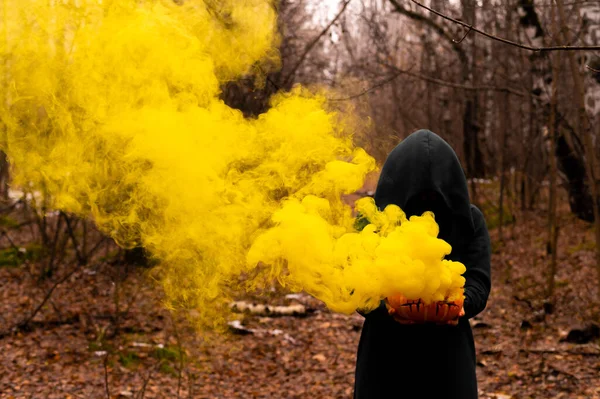 Una strega raccapricciante tiene una zucca fumante in una foresta profonda. Jack o lanterna emette fumo giallo per Halloween — Foto Stock