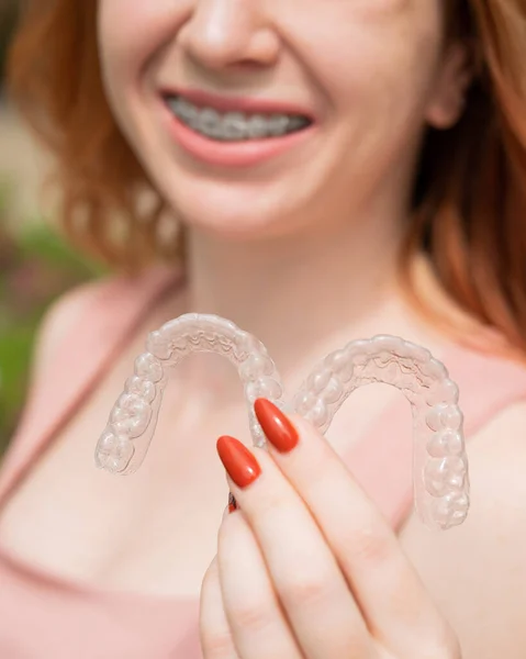 Mooie jonge roodharige vrouw met beugels op haar tanden houden uitneembare beugels buiten — Stockfoto