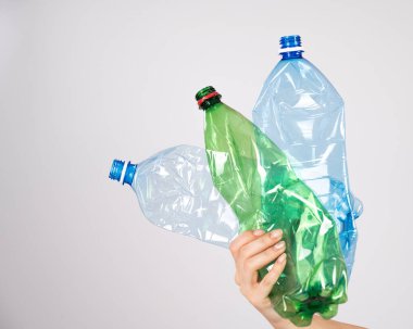 Beyaz arka planda plastik şişe tutan bir kadının yakın çekimi..