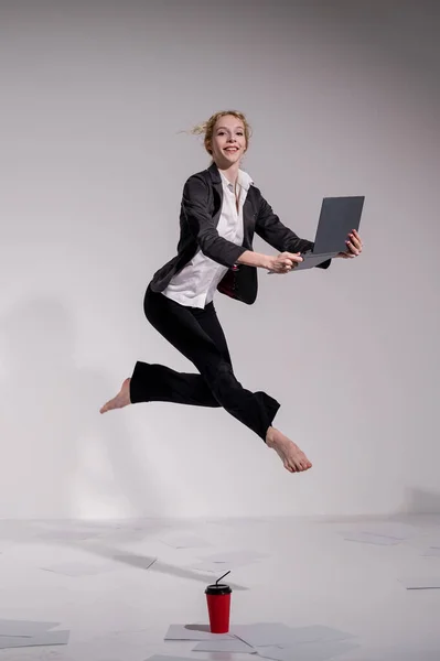 Barfota ballerina klädd i en kostym utgör för en bärbar dator och dricker kaffe. Flexibel kvinna arbetar vid datorn — Stockfoto