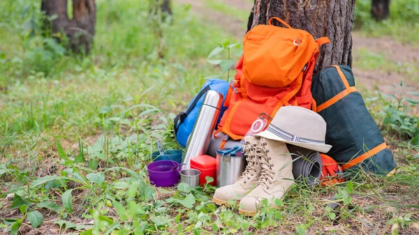 Equipo de senderismo en un bosque de pinos. Mochila, termo, saco de dormir, brújula, sombrero y zapatos —  Fotos de Stock