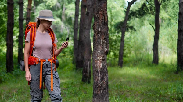 Jeune femme caucasienne fait de la randonnée et utilise une boussole dans la forêt. — Photo