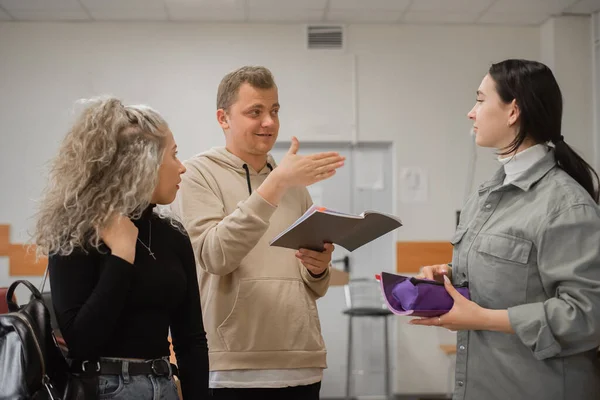 Zwei Mädchen und ein Mann unterhalten sich in Gebärdensprache. Drei gehörlose Studenten unterhalten sich in einem Hörsaal der Universität. — Stockfoto