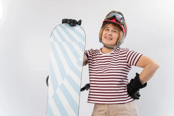 Porträt einer lächelnden älteren Frau in rosa Skihelmhandschuhen und mit Snowboard auf weißem Hintergrund. — Stockfoto