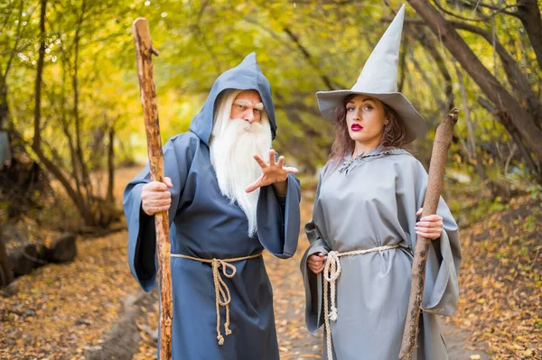 Mago y hechicera en el bosque otoñal. Anciano hombre y mujer en trajes de carnaval para Halloween — Foto de Stock