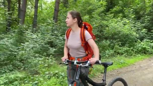 Mujer caucásica monta una bicicleta en el bosque — Vídeos de Stock