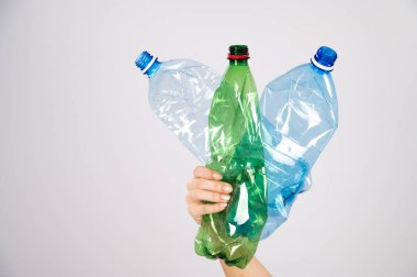 Beyaz arka planda plastik şişe tutan bir kadının yakın çekimi..