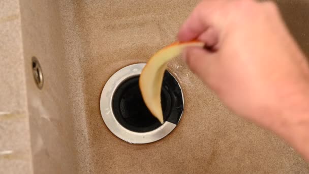 Un homme met des croûtes de melon dans une décharge de déchets alimentaires. Dispositif intégré dans l'évier de cuisine. — Video