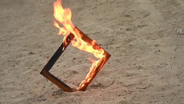 Houten fotolijstje in brand op het strand. — Stockvideo