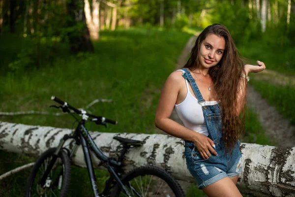 Mujer joven está descansando mientras pedalea en el bosque — Foto de Stock