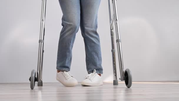 Gros plan des jambes féminines avec marchettes. La fille marche avec l'aide d'un équipement spécial. — Video