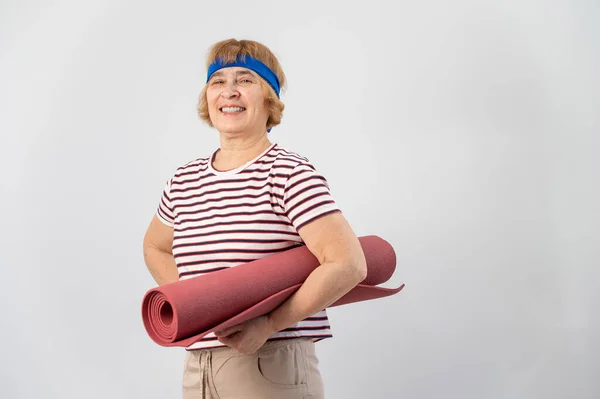 Äldre kaukasiska kvinna som håller i vikbar yogamatta i studio. — Stockfoto