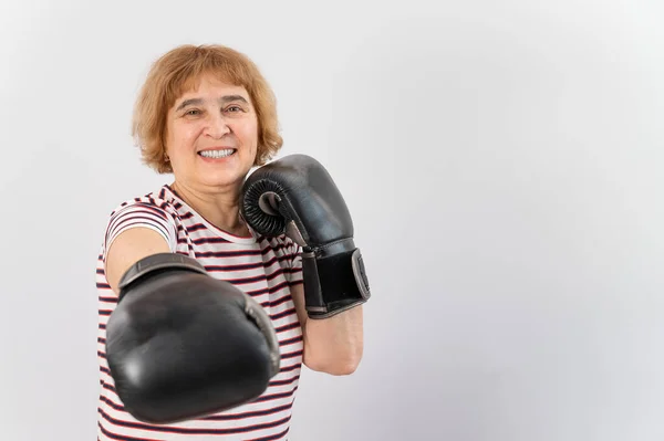 Äldre kvinna i kampen handskar i en defensiv pose på en vit bakgrund. — Stockfoto