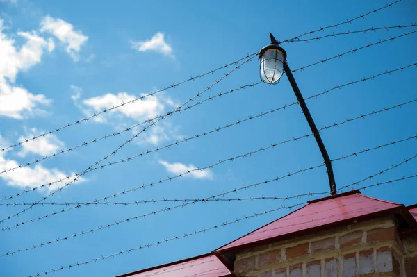 Prikkeldraad op het hek van de gevangenis tegen de blauwe lucht — Stockfoto