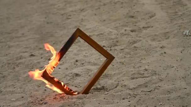 Drewniana ramka na zdjęcia w ogniu na plaży. — Wideo stockowe