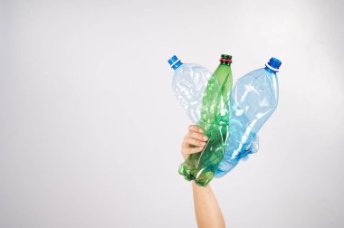 Beyaz arka planda plastik şişe tutan bir kadının yakın çekimi..