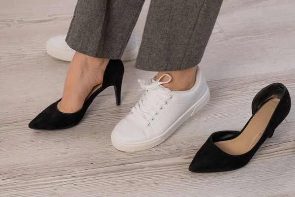 Close-up zakenvrouw neemt uit haar schoenen zet op wit lederen sneakers. — Stockfoto