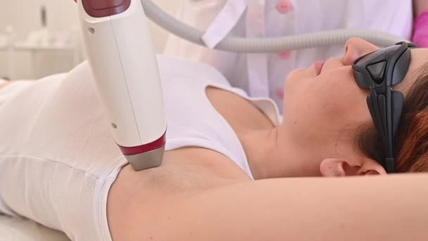 Az orvos lézeres szőrtelenítést végez egy női hónaljon a szalonban. Alternatív módszer a nem kívánt testszőrzet végleges eltávolítására — Stock videók
