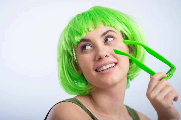 Jovem alegre em peruca verde e óculos engraçados celebrando dia st patricks em um fundo branco — Fotografia de Stock