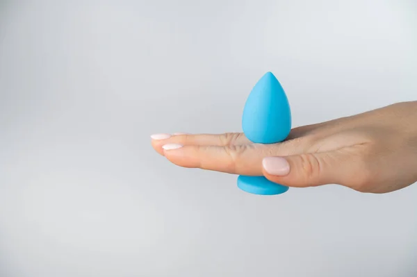 Woman holding a blue butt plug on a white background. Adult toy for alternative sex — Zdjęcie stockowe