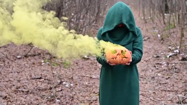 Una strega raccapricciante tiene una zucca fumante in una foresta profonda. Jack o lanterna emette fumo giallo per Halloween. — Video Stock