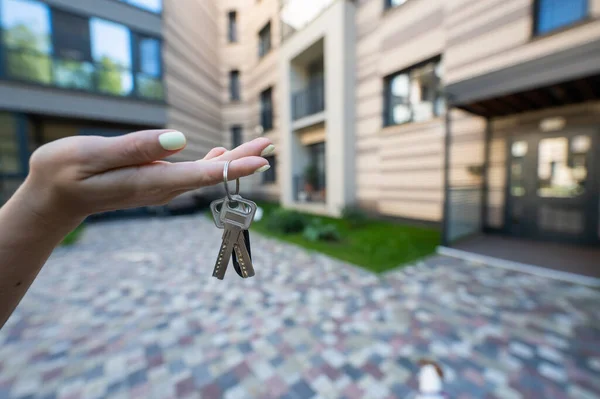 A woman holds the keys to a new house. Close-up of a female hand. Buying a property.