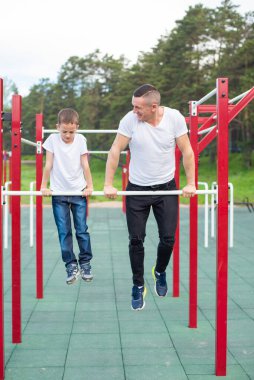 Kafkasyalı bir adam oyun parkındaki düzensiz barlarda bir çocuğu eğitiyor. Baba ve oğul açık hava sporlarına gider..