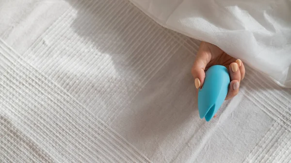 A faceless woman lies in bed under a blanket holding a clitoral vibrator. The girl masturbates — Stock Photo, Image