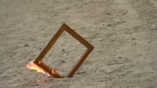 Cadre photo en bois en feu sur la plage. — Video