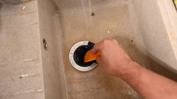 En man lägger melonskorpor i en matavfallskvarn. Inbyggd anordning i diskbänken. — Stockvideo