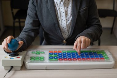 Serebral felçli tanınmayan bir kadın klavyede yazı yazıyor. Özürlü bir kız özel donanımlı bir bilgisayarda çalışır.