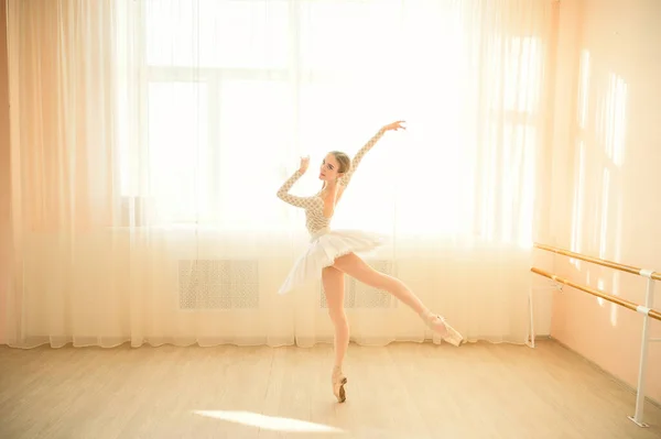 Hermosa bailarina en cuerpo y tutú blanco está entrenando en una clase de baile. Joven bailarina flexible posando en zapatos puntiagudos. — Foto de Stock