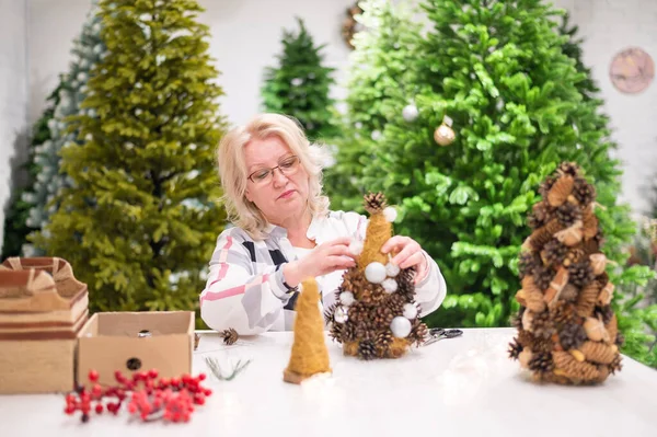 Äldre kaukasiska kvinna gör koner dekoration för jul. — Stockfoto