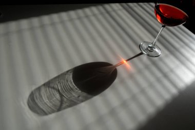 Perdelerden uzak beyaz bir masada bir kadeh kırmızı şarap.