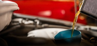 Otomobil tamircisi araba motoruna yağ döker.