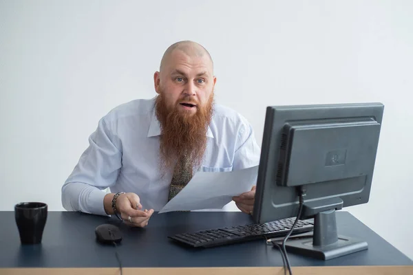 Porträtt av en skallig man vid ett skrivbord som tittar på en rapport och svär. Den missnöjde chefen avskedar den underordnade. — Stockfoto