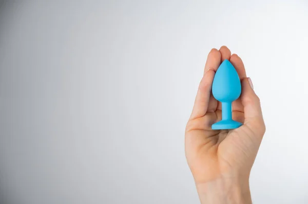 Woman holding a blue butt plug on a white background. Adult toy for alternative sex — Stok Foto