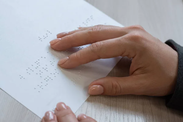 La mujer de cerca lee el texto a los ciegos. Mujeres manos sobre papel con código braille. — Foto de Stock