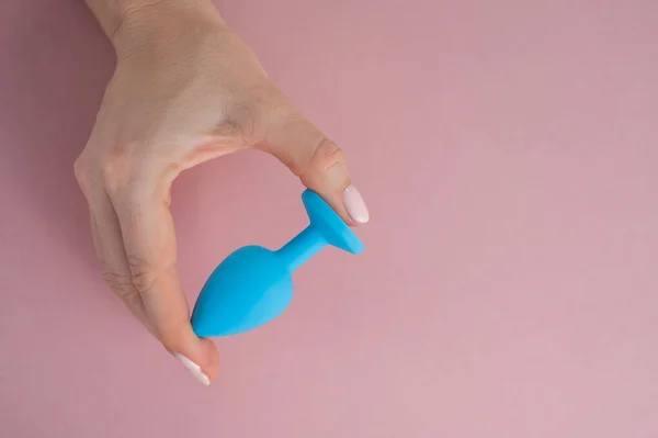 Жінка тримає блакитний анальний штепсель на рожевому тлі. Іграшка для дорослих для альтернативного сексу — стокове фото