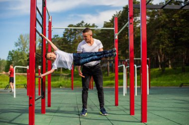 Kafkasyalı bir adam çocuk parkında bayrak dikmeyi öğretiyor..