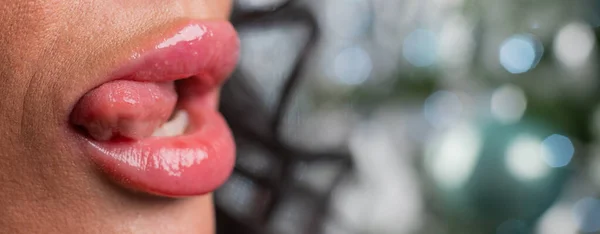 Close-up of large plump female lips against a background of christmas decorations. — Stock Photo, Image