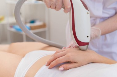 Lazer epilasyon prosedürü uygulayan bir kadın. İstenmeyen bitki örtüsünün donanımla kaldırılması