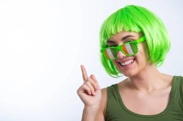 Joyeux jeune femme en perruque verte et lunettes drôles célébrant st patricks jour sur un fond blanc — Photo