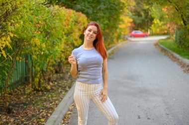 Güzel kızıl saçlı kadın sonbaharda dışarıda poz veriyor..