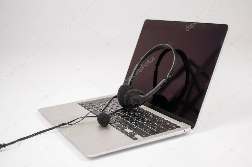 Headset on laptop keyboard on white background.