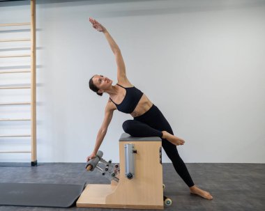 Beyaz kadın klasik sandalyede pilates yapıyor.